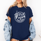 A woman wearing an oversized navy blue graphic t-shirt with a white circular design featuring a hand gesture and the text 'Fuck YOUR FEELINGS'. She has a light-wash denim jacket draped off her shoulders and is standing against a plain white wall. Purchase from Coffee and Moo NZ.