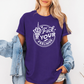 A woman wearing a purple short-sleeve graphic t-shirt with a white circular design that reads 'Fuck YOUR FEELINGS' and shows a middle finger skeleton hand. She has a light blue denim jacket draped off her shoulders and is posing against a plain white wall. Purchase from Coffee and Moo NZ.
