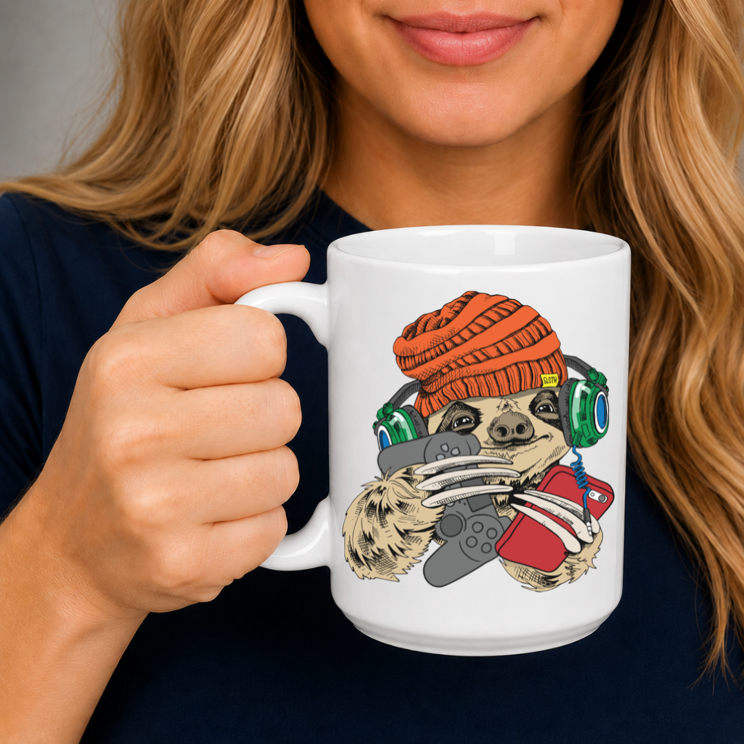 A person holding a white ceramic mug with a colorful cartoon graphic of a sloth wearing an orange knit hat and holding a game controller. The person is wearing a dark navy blue shirt against a neutral grey background. Grab your gaming sloth mug from Coffee and Moo NZ. 