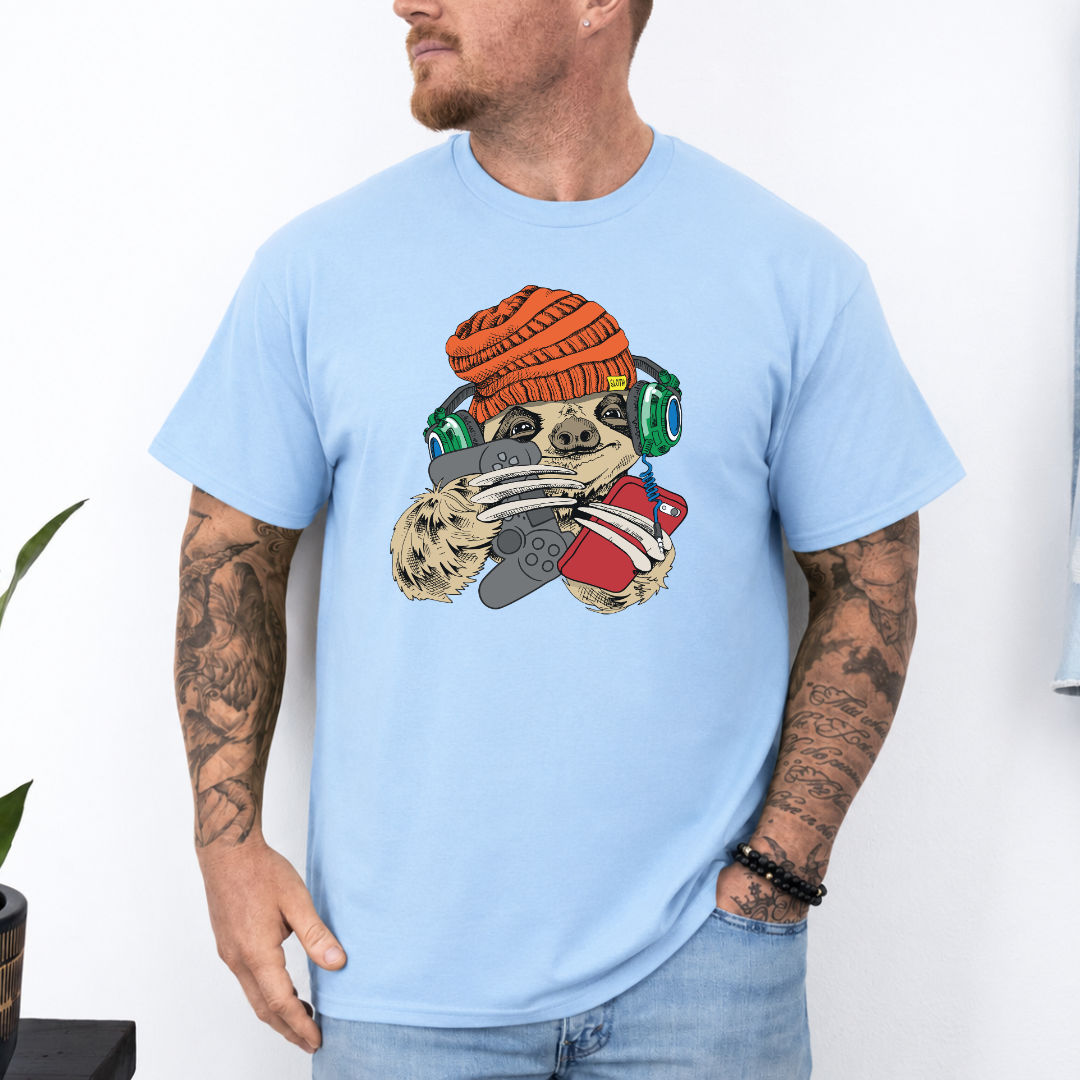 Male wearing a baby blue graphic T-shirt  featuring a colorful cartoon sloth wearing an orange knit beanie, green headphones, while holding a red phone and grey controller. Grab your tee from Coffee and Moo NZ.