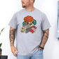Male wearing a grey graphic T-shirt  featuring a colorful cartoon sloth wearing an orange knit beanie, green headphones, while holding a red phone and grey controller. Grab your tee from Coffee and Moo NZ.