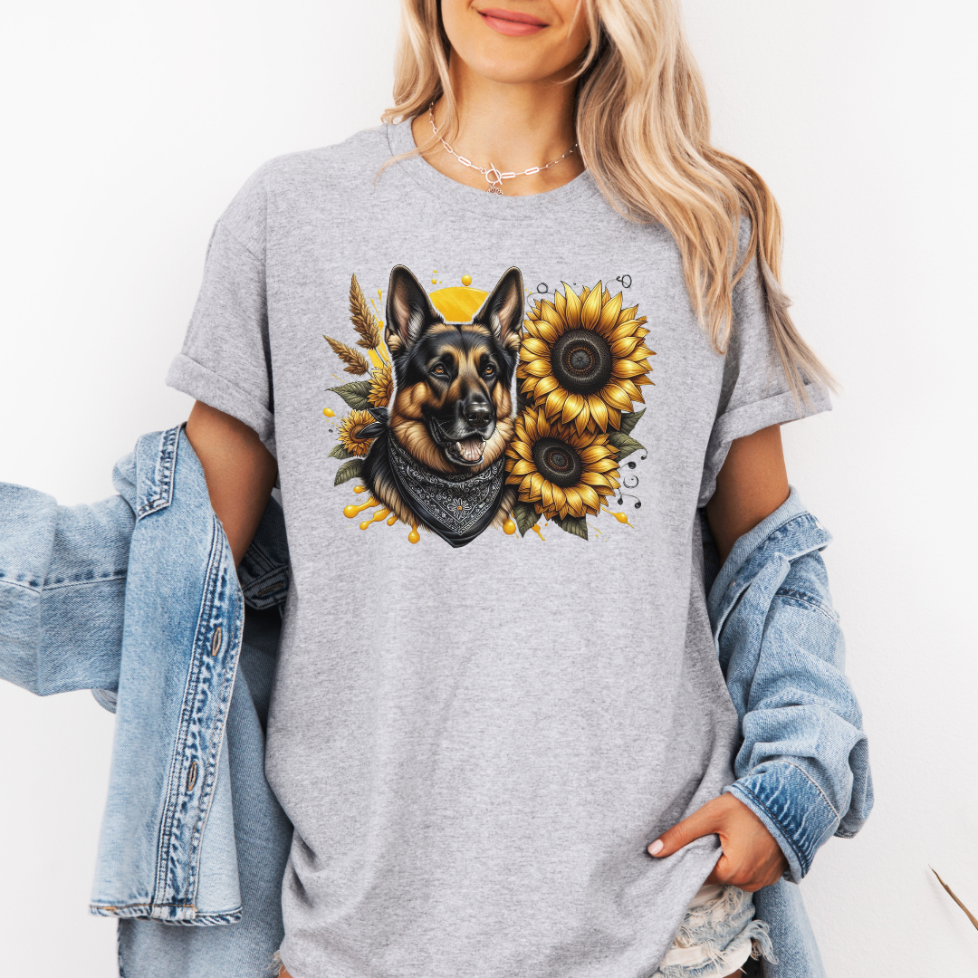 A man wearing a grey short-sleeve t-shirt with a graphic print of a German Shepherd dog surrounded by yellow sunflowers, paired with light blue jeans. Grab your tee from Coffee and Moo NZ.