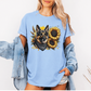 A man wearing a light blue short-sleeve t-shirt with a graphic print of a German Shepherd dog surrounded by yellow sunflowers, paired with light blue jeans. Grab your tee from Coffee and Moo NZ.