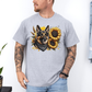 A man wearing a grey short-sleeve t-shirt with a graphic print of a German Shepherd dog surrounded by yellow sunflowers, paired with light blue jeans. Grab your tee from Coffee and Moo NZ.