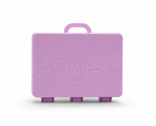 A lilac rectangular carrying case with a top handle, featuring the words 'Getting Lost' embossed on the front, set against a plain white background. For the Getting lost card game. Purchase from Coffee and Moo