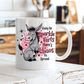 A white ceramic coffee mug with a cartoon donkey and the text 'Giddy Up Sparkle Farts There's Chaos to Spread.' sitting on a rustic white wooden table with a blurred kitchen background. from Coffee and Moo.