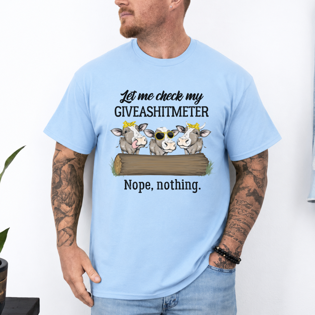 A man wearing a light blue graphic t-shirt with a humorous cow design and the text 'Let me check my GIVEASHITMETER Nope, nothing.'. Grab your from Coffee and Moo NZ.