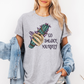A woman wearing a heather gray graphic t-shirt with a hand holding a green and purple smudge bundle and the text 'GO SMUDGE YOURSELF'. She has a light blue denim jacket draped off her shoulders against a plain white background. Purchase from Coffee and Moo NZ.