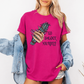 A woman wearing a bright pink graphic t-shirt with a hand holding a green smudge bundle and the text 'GO SMUDGE YOURSELF'. She has a light blue denim jacket off her shoulders and is posing against a plain white background. Purchase from Coffee and Moo NZ.