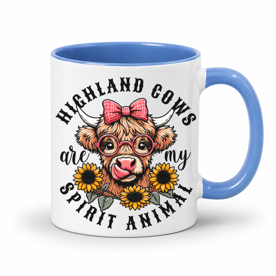 A white ceramic mug with a blue interior and handle, featuring a cartoon Highland cow with a pink bow, glasses, and sunflowers, surrounded by the text 'HIGHLAND COWS are my SPIRIT ANIMAL'. from Coffee and Moo NZ.