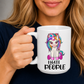 A person holding a white ceramic mug with a cartoon unicorn graphic and the text 'I HATE PEOPLE' printed on it. The person is wearing a dark navy shirt, and the background is a soft gray studio backdrop. From Coffee and Moo NZ.