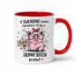 A white ceramic mug with a red interior and red handle, featuring a cartoon pink pig wearing glasses and a red bow headband, holding a sign that says 'FUCK', with text above and below reading 'IF SWEARING BURNED CALORIES I'D BE A SKINNY BITCH BY NOW!'. from Coffee and Moo.