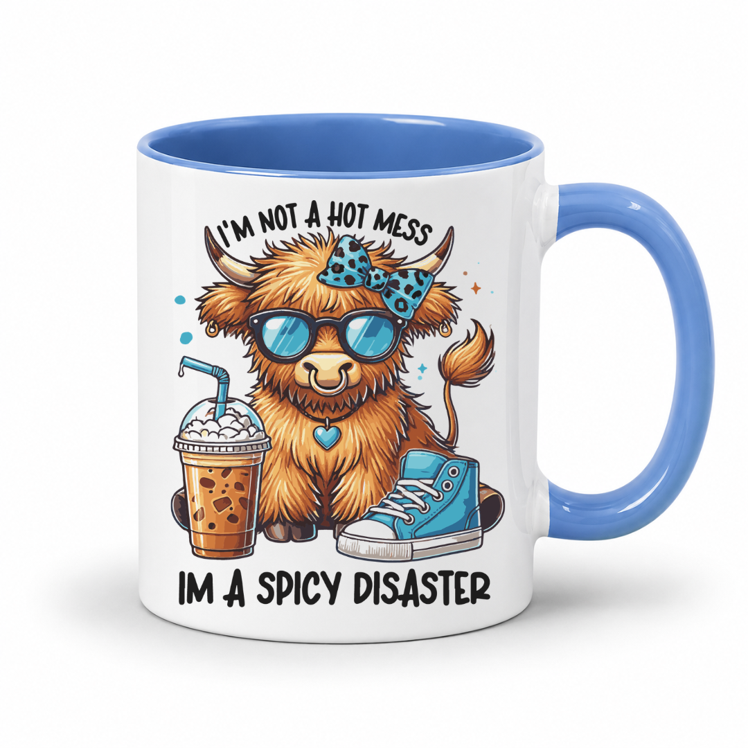 A white ceramic coffee mug with a blue interior and handle, featuring a cartoon highland cow wearing sunglasses and a bow tie, with the text 'I'M NOT A HOT MESS' and 'IM A SPICY DISASTER'. from Coffee and Moo NZ.