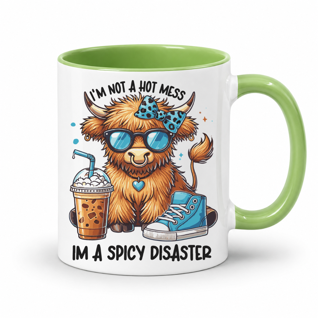 A white ceramic mug with a light green handle and interior, featuring a cartoon illustration of a fluffy brown animal wearing blue sunglasses and a blue patterned bow tie, with the text 'I'M NOT A HOT MESS IM A SPICY DISASTER'. from Coffee and Moo NZ.