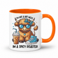 A white ceramic coffee mug with a bright orange handle and interior, featuring a cartoon illustration of a fluffy brown animal wearing blue sunglasses and a blue bow tie, next to an iced coffee and a blue sneaker. The text reads 'I'M NOT A HOT MESS' above the illustration and 'IM A SPICY DISASTER' below. from Coffee and Moo NZ.