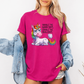 A woman wearing a bright pink graphic t-shirt with a cartoon unicorn and the text 'INHALE THE GOOD SHIT, EXHALE THE BULLSHIT.' She has a light blue denim jacket off her shoulders against a plain white background.  Purchase from Coffee and Moo NZ.