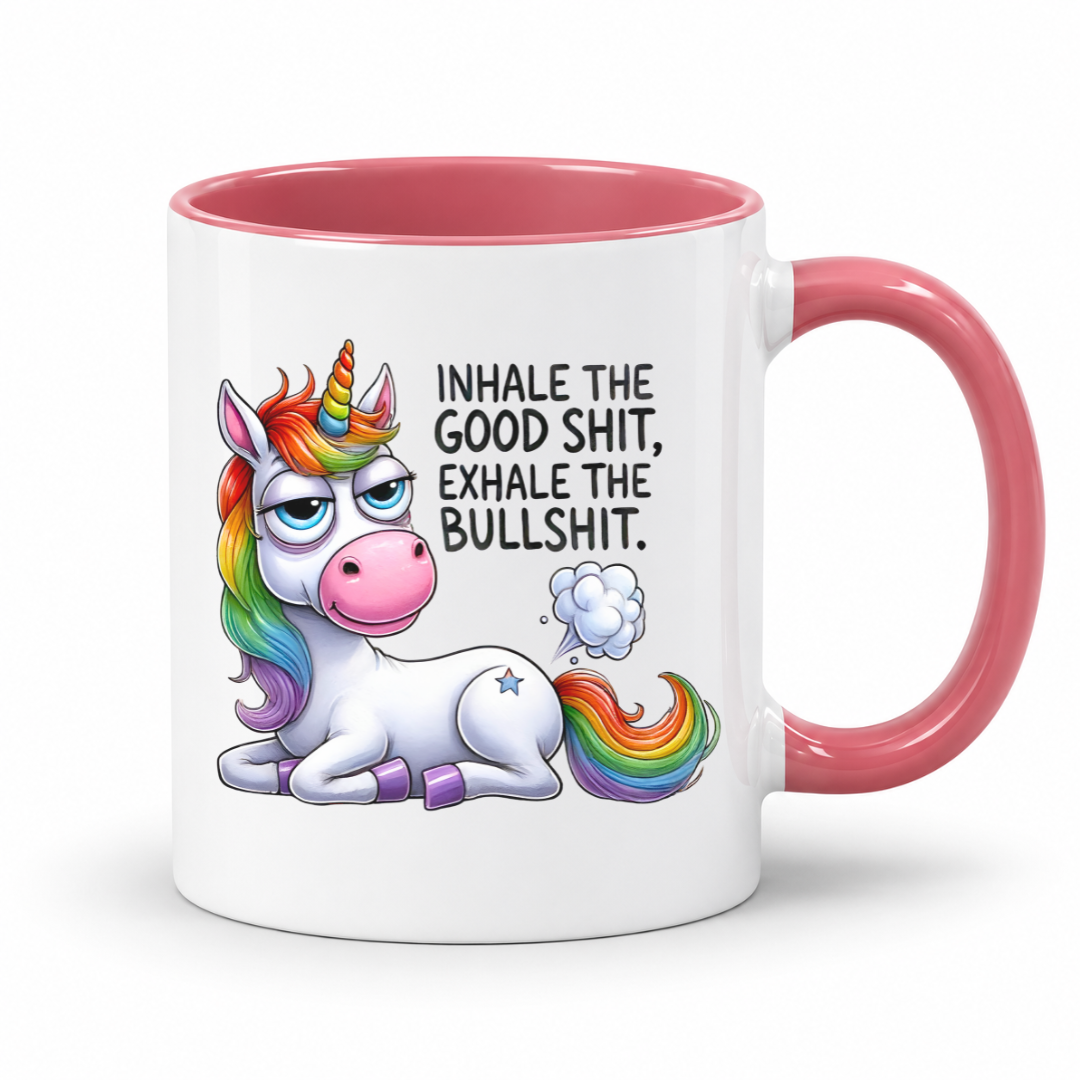 A white ceramic mug with a pink interior and handle, featuring a cartoon rainbow unicorn and the text 'INHALE THE GOOD SHIT, EXHALE THE BULLSHIT.' on the front, shown on a clean white background. Purchase from Coffee and Moo NZ.