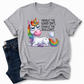 A grey short-sleeve t-shirt with a graphic of a cartoon unicorn and the text 'INHALE THE GOOD SHIT, EXHALE THE BULLSHIT.' styled flat-lay next to a pair of dark blue jeans on a white background. Grab your tee from Coffee and Moo NZ.