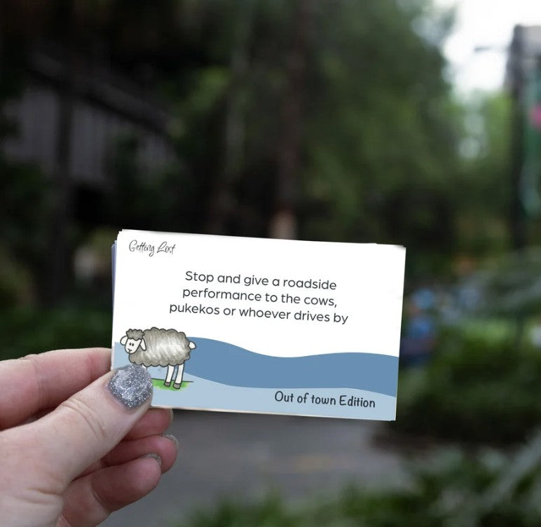 Discover rural NZ with the Getting Lost Kiwi Out of Town card game. Image shows text " stop and give a roadside performance to cows, pukekos or whoever drives by. there is 15 direction + activity cards. grab yours from coffee and moo NZ.
