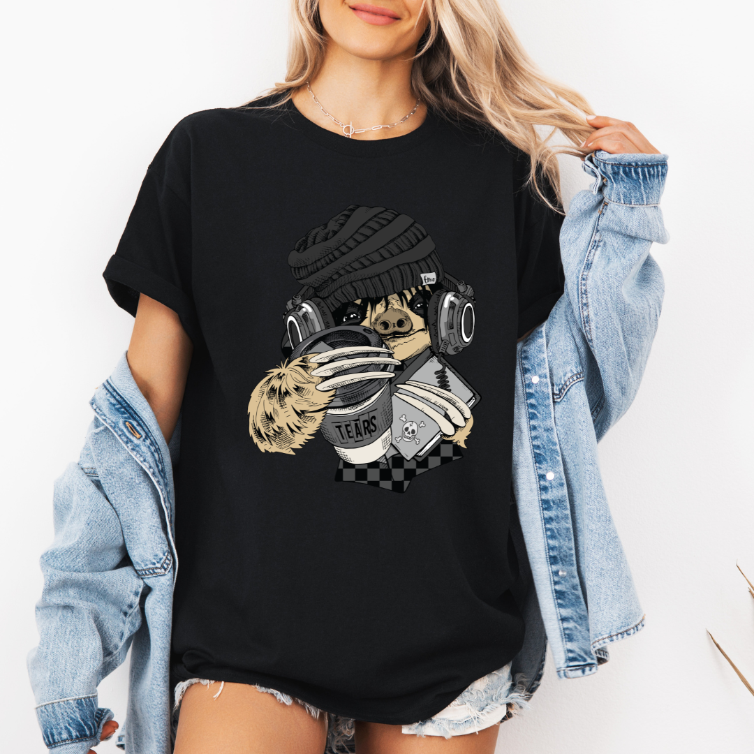A woman wearing a black short-sleeve graphic t-shirt with a stylized Emo sloth wearing a beanie, headphones, and holding a coffee cup with the word "TEARS" on it. Grab your tee from Coffee and Moo NZ.