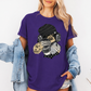 A woman wearing a purple short-sleeve graphic t-shirt with a stylized Emo sloth wearing a beanie, headphones, and holding a coffee cup with the word "TEARS" on it. Grab your tee from Coffee and Moo NZ.