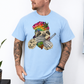 A man wearing a baby blue unhinged adult graphic tee features our resident zen master—a delightfully baked sloth rocking a vibrant, colourful tie-dye beanie topped with a cannabis leaf, proudly clutching a bong and a jar of premium green buds. Grab your sloth stoner tee from Coffee and Moo NZ.
