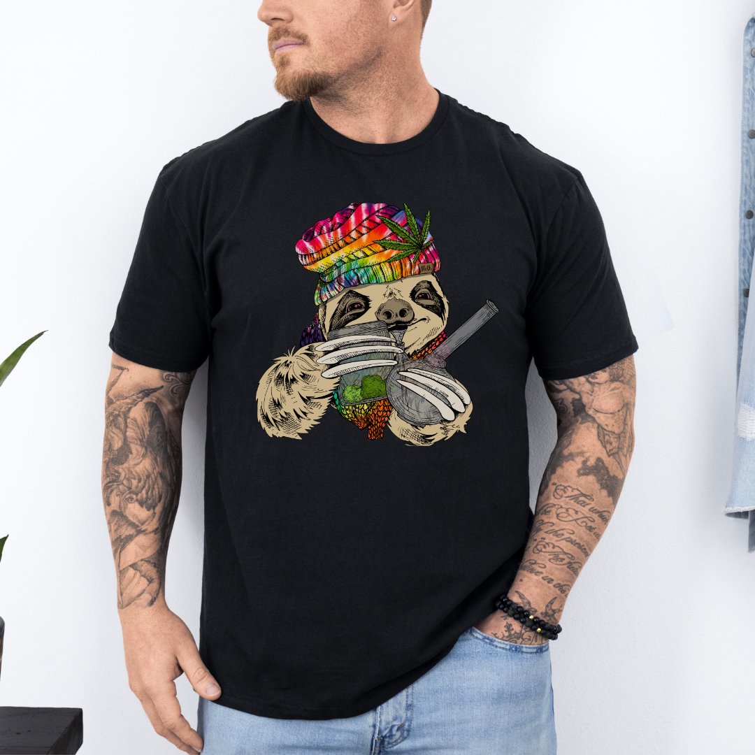 A man wearing a black unhinged adult graphic tee features our resident zen master—a delightfully baked sloth rocking a vibrant, colourful tie-dye beanie topped with a cannabis leaf, proudly clutching a bong and a jar of premium green buds. Grab your sloth stoner tee from Coffee and Moo NZ.