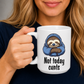 A person holding a white ceramic mug with a cartoon sloth wearing a blue hoodie and the text 'Not today cunts' printed on it. The person is wearing a dark navy shirt, and the background is a soft gray studio backdrop.  from Coffee and Moo.