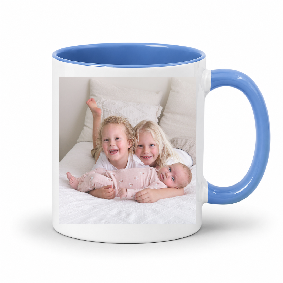 A white ceramic mug with a blue interior and blue handle, featuring a printed custom photo of three children. Grab your custom photo mug from Coffee and Moo NZ.