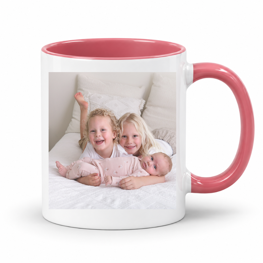 A white ceramic mug with a coral pink interior and handle, featuring a printed custom family photo on the front, set against a plain white background. Grab your custom photo mug from Coffee and Moo NZ.