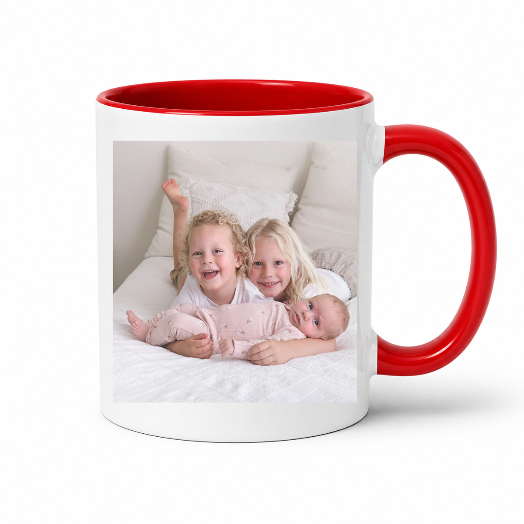 A white ceramic mug with a bright red handle and interior, featuring a printed custom kids photo on the front, set against a plain white background. Grab your custom photo mug from Coffee and Moo NZ.
