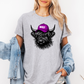 A woman wearing a heather gray oversized t-shirt with a graphic of a black Scottish Highland cow wearing a purple cap that says 'BOSSY' in white. She has a light blue denim jacket draped off her shoulders against a plain white background. Grab your Bossy highland coo tee from Coffee and Moo NZ.