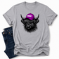 A heather gray short-sleeve t-shirt with a graphic of a black highland cow wearing a purple cap that says 'BOSSY' in white letters. The t-shirt is styled flat-lay with dark blue jeans on a white background. Grab your Bossy highland coo tee from Coffee and Moo NZ.