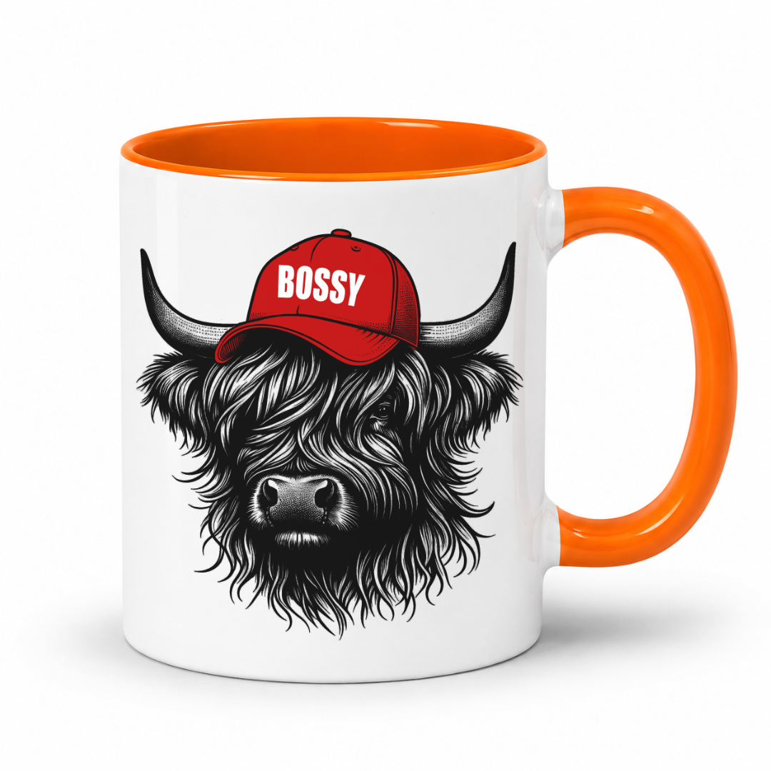 A white ceramic mug with a bright orange handle and interior, featuring a black-and-white illustration of a shaggy Highland cow wearing a red cap with the word 'BOSSY' in white. Grab your Bossy highland coo mug from Coffee and Moo NZ.