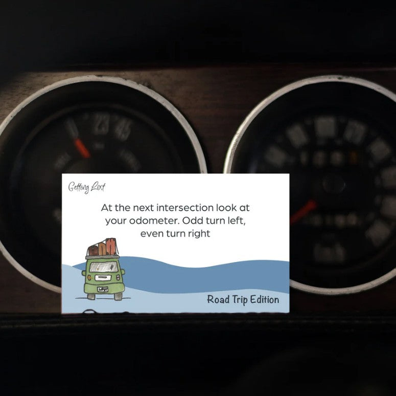 Image features a card from the Getting Lost Road Trip Edition Adventure Card Game with the text " At the next intersection look at the odometer. Odd turn left, Even turn right". The pack features 26 direction + activity cards. Grab yours for your next road trip from Coffee and Moo NZ