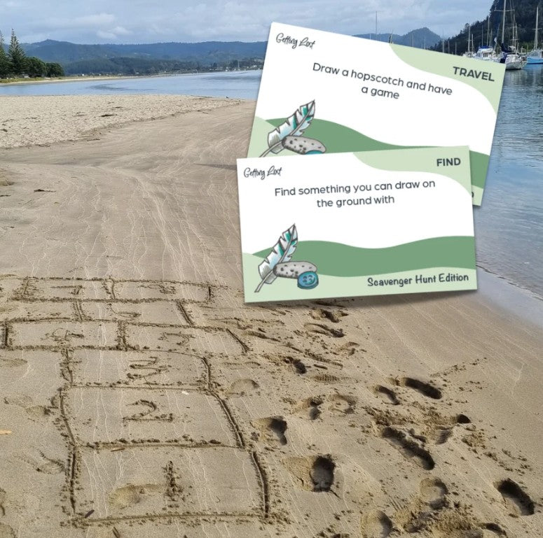 The Getting Lost Scavenger Hunt Edition. image shows 2 cards from the game. The cards show prompts like The cards read - Draw a hopscotch and have a game and 'Find something you can draw on the ground with' Grab your game today from Coffee and moo NZ.
