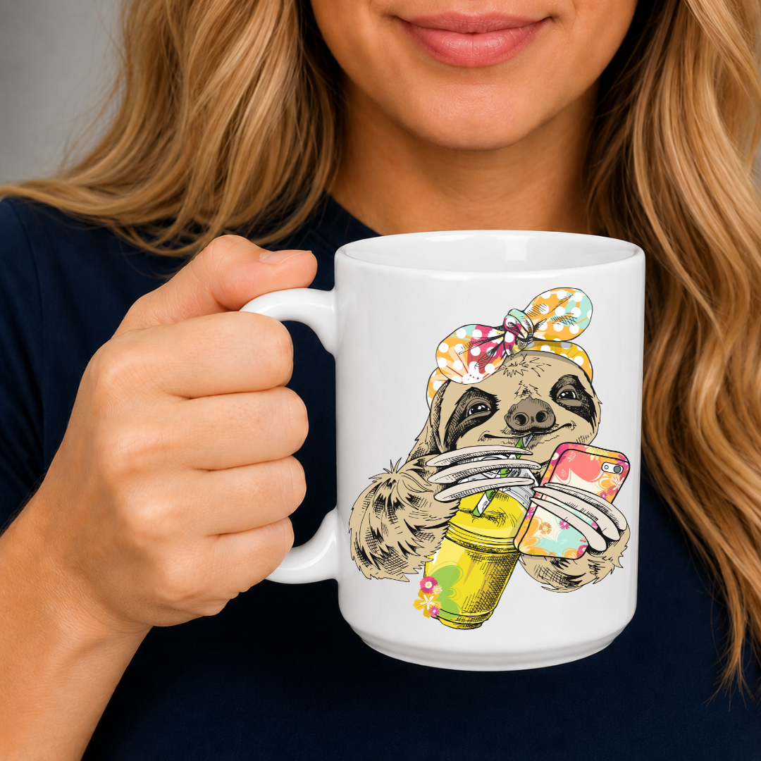 A person holding a white ceramic mug with a colorful illustration of a sloth wearing a polka-dot bow bandana and holding a loaded-tea drink and a phone. Grab yours from Coffee and Moo NZ.