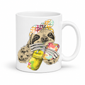 A white ceramic mug with a colorful illustration of a sloth wearing a polka dot bandana and holding a loaded-tea drink and a phone, set on a  white  background. Grab yours from Coffee and Moo NZ.