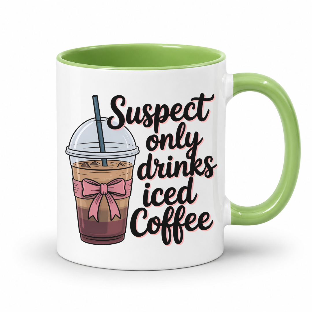 A white ceramic coffee mug with a light green handle and interior, featuring a printed graphic of an iced coffee cup with a pink bow and the text 'Suspect only drinks iced Coffee' in black script with a pink outline. From Coffee and Moo NZ.