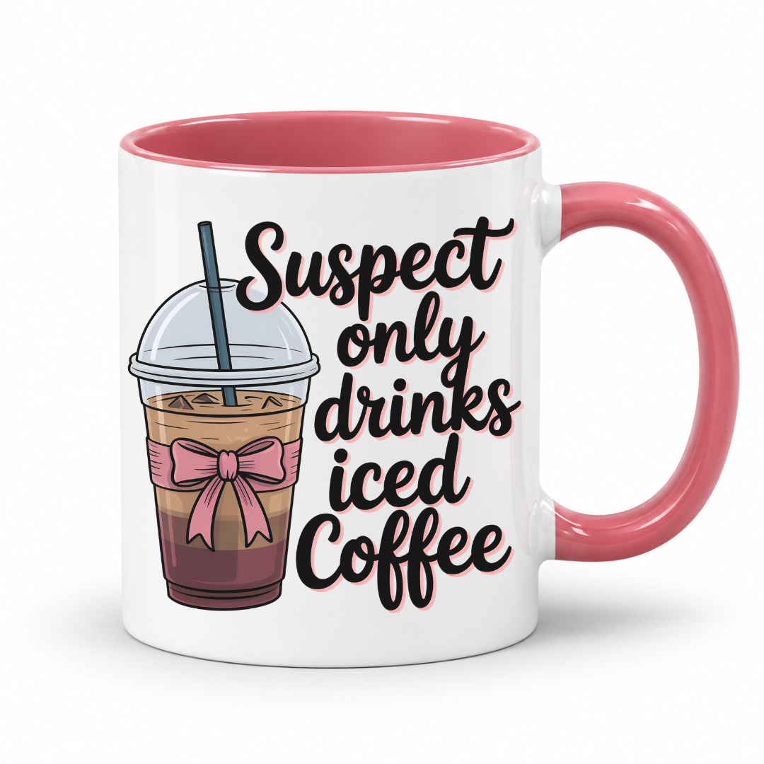 A white ceramic coffee mug with a pink interior and handle, featuring a cartoon iced coffee cup with a pink bow and the text 'Suspect only drinks iced Coffee' in black script. From Coffee and Moo NZ.