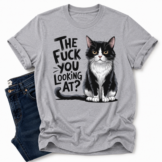 A grey short-sleeve t-shirt with a graphic of a black and white cat and the text 'THE FUCK YOU LOOKING AT?' printed on the front, styled flat-lay next to a pair of dark blue jeans on a white background. Grab your feral tee from Coffee and Moo NZ.