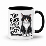 A white ceramic coffee mug with a black interior and black handle, featuring a black and white cat illustration and the text 'THE FUCK YOU LOOKING AT?' printed on the side.