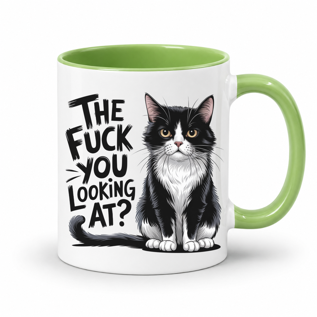 A white ceramic coffee mug with a light green interior and handle, featuring a black and white cat illustration and the text 'THE FUCK YOU LOOKING AT?' printed on the side.