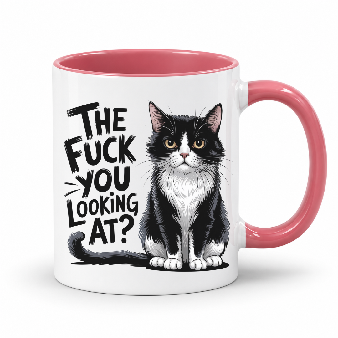 A white ceramic mug with a pink interior and handle, featuring a black and white tuxedo cat illustration and the text 'THE FUCK YOU LOOKING AT?' in black stylized lettering.