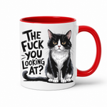 A white ceramic coffee mug with a red interior and red handle, featuring a black and white cat illustration and the text 'THE FUCK YOU LOOKING AT?' in black lettering.