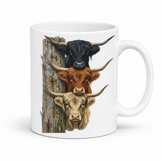 A white ceramic mug featuring a printed graphic of three Scottish Highland cattle heads stacked vertically next to a weathered wooden post. From Coffee and Moo NZ