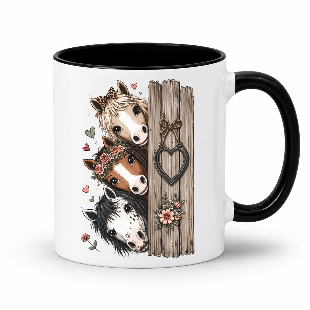 A white ceramic mug with a black interior and black handle, featuring a printed illustration of three cute horses peeking from behind a rustic wooden fence with a heart-shaped ornament. From Coffee and Moo