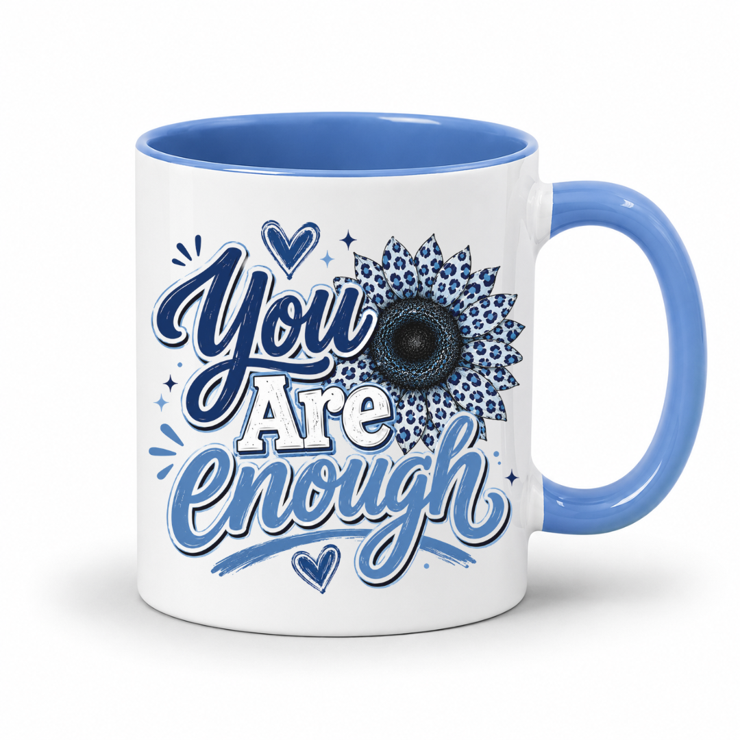 A white ceramic mug with a blue interior and handle, featuring the printed text 'You Are Enough' in blue script and a blue sunflower design on the front. Purchase yours from Coffee and Moo.